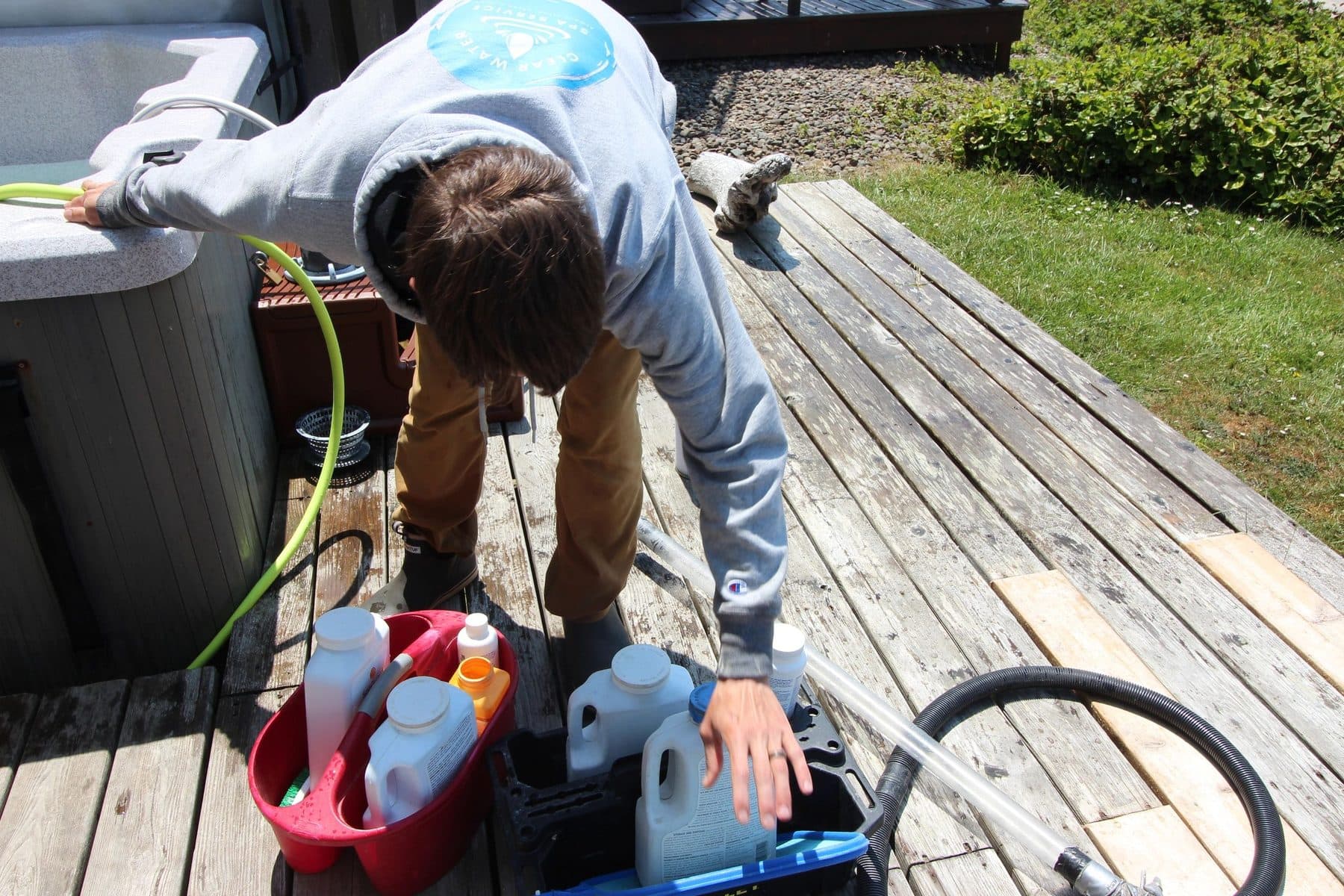 Chemicals and equipment staged on a deck for a hot tub drain and fill
