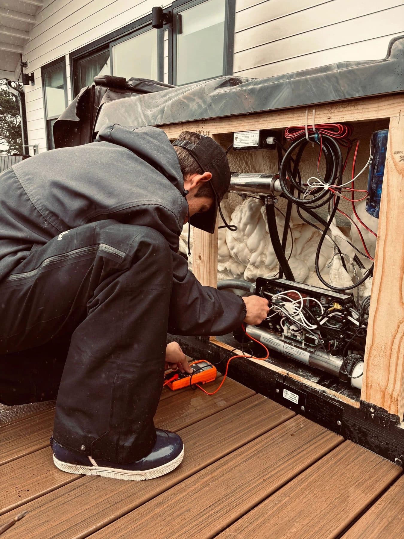 Technician repairing hot tub electrical components behind an access panel